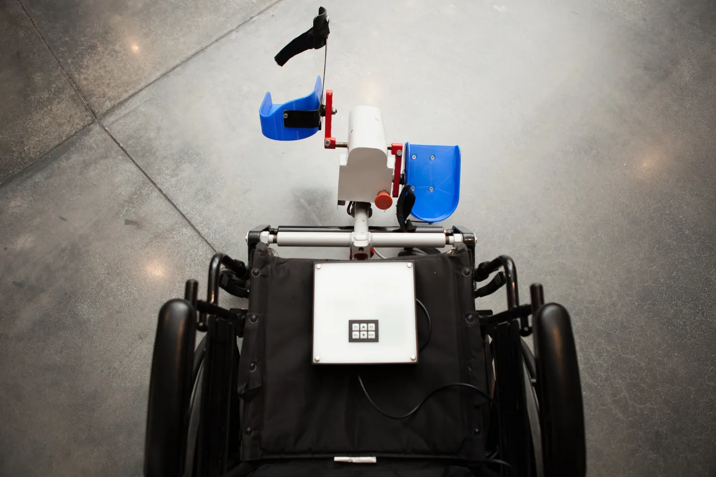 View from above of LegMaker prototype blue pedals and control panel mounted on a manual wheelchair